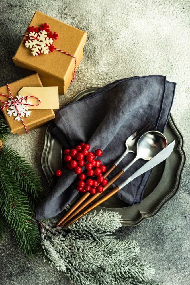 Christmas gifts with pine and gingerbread ornament next to plate