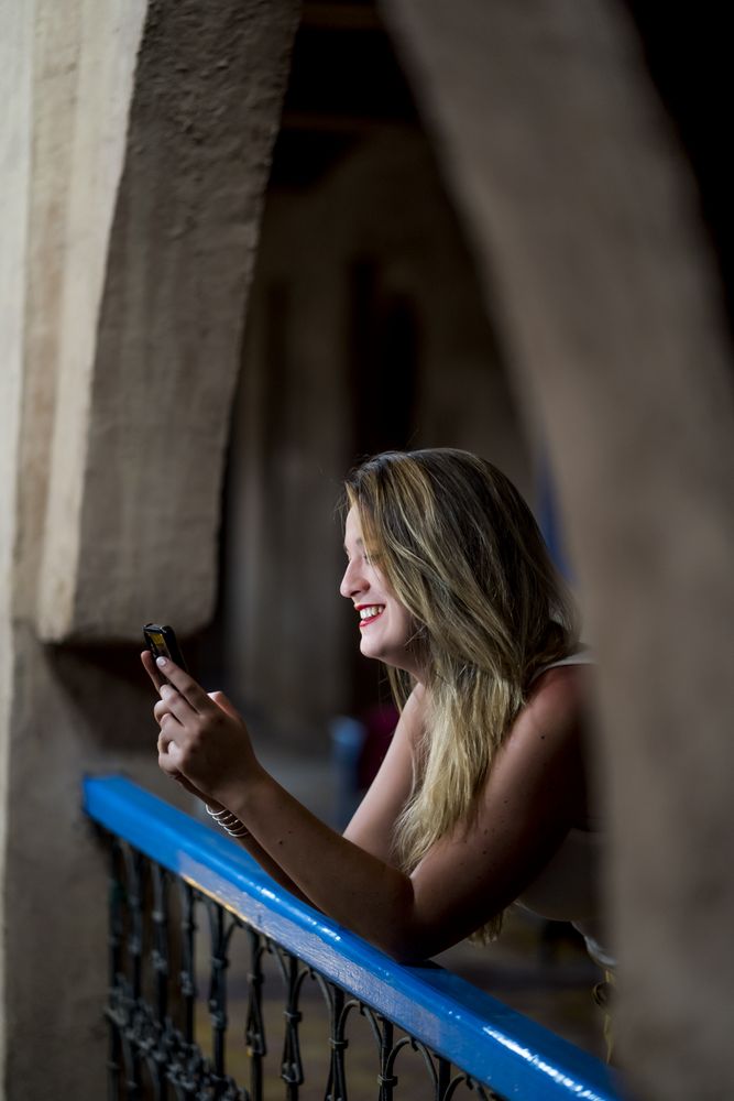 Smiling woman using smartphone on old balcony
