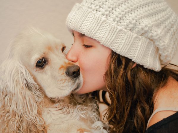 Teen in hat kissing dog