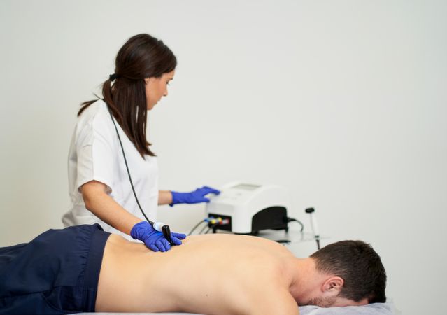 A female physiotherapist giving diathermy treatment on the patie