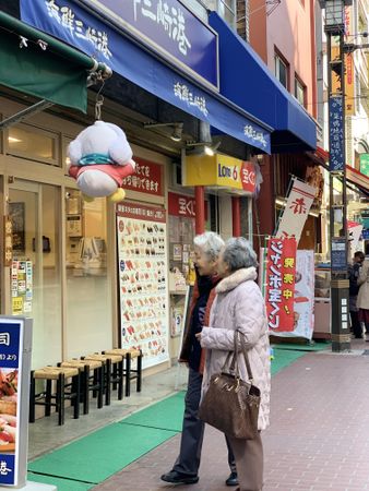 Two older people standing on sidewalk