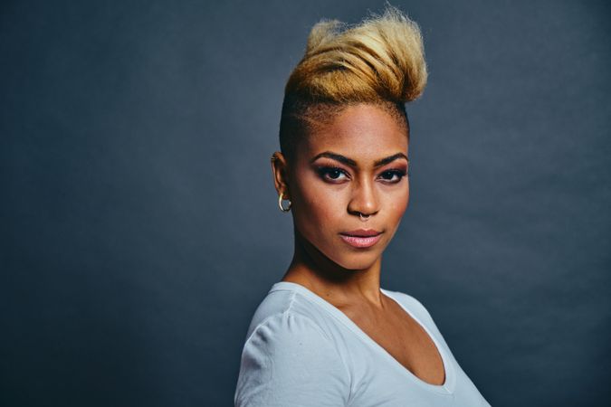 Portrait of proud Black woman with short blonde hair against gray background with copy space