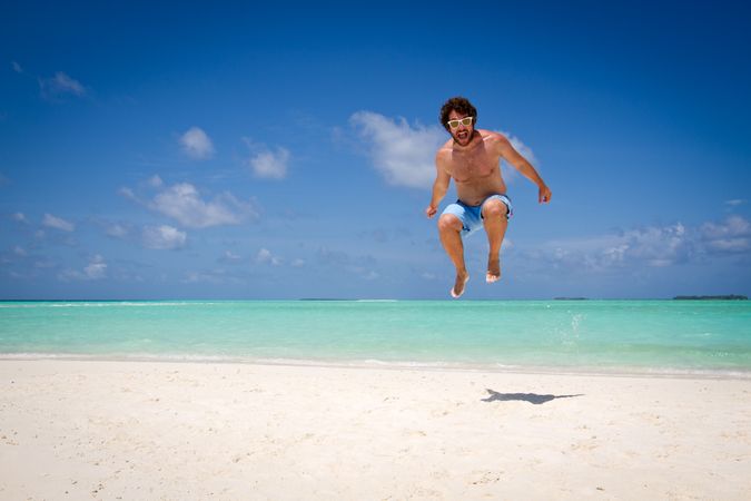 Man jumping near turquoise sea