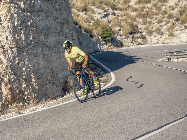 healthy man riding a bicycle on a mountain road in a sunny day