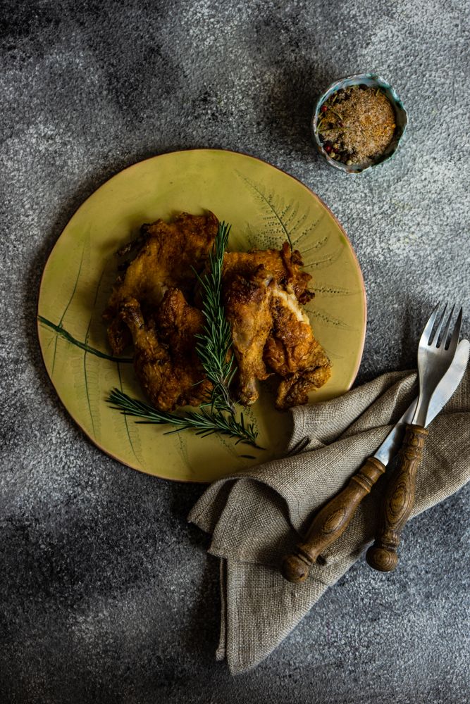 Top view plate of grilled chicken with rosemary with cutlery