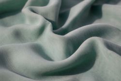 Nude green fabric wavy crumpled background texture with copy space.