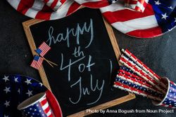 Chalkboard surrounded by USA flag plates, cups and straws, with the words "Happy 4th of July" 5qk37K