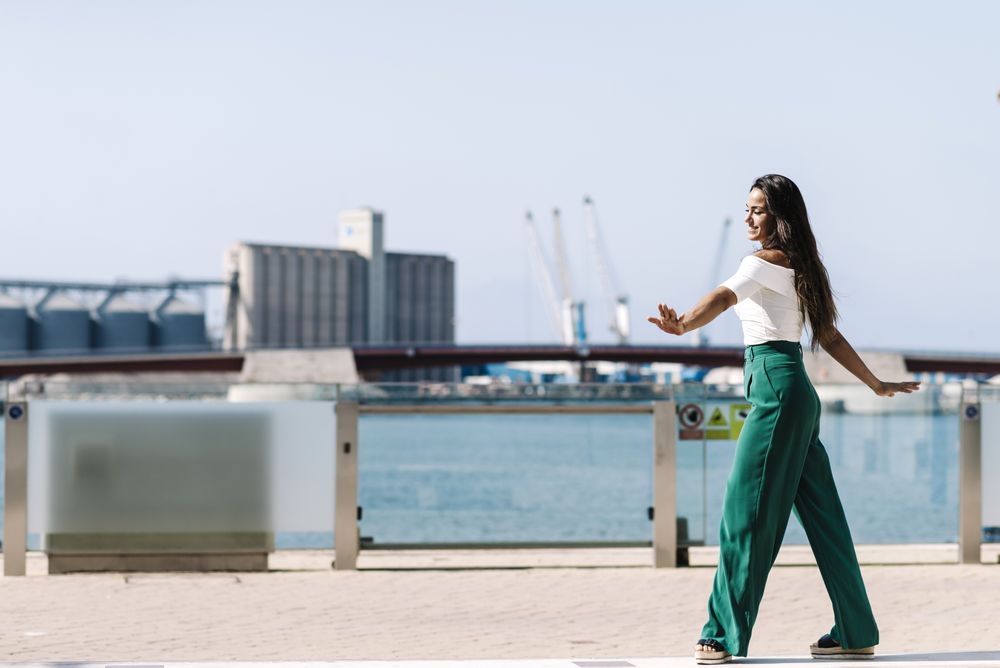 Young woman walking dancing on city street on daylight
