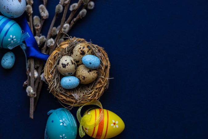Top view of blue table and bird's nest with colorful eggs for Easter card concept
