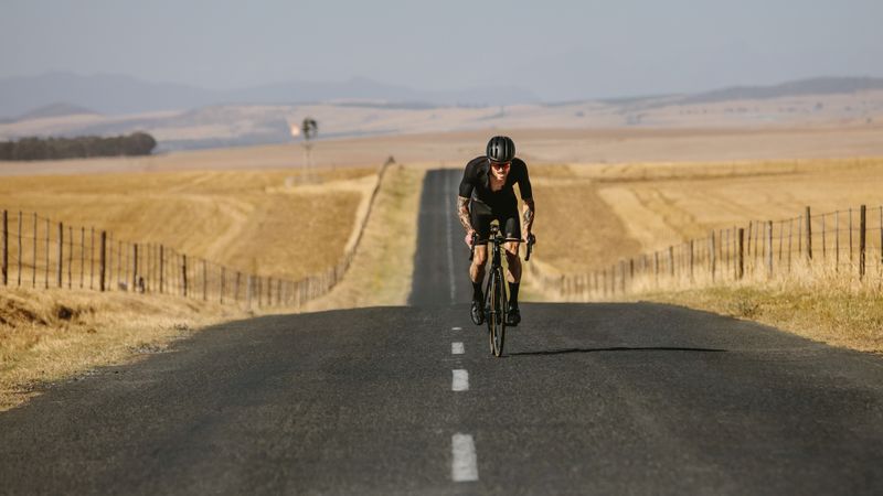 Athlete cycling on empty rural highway