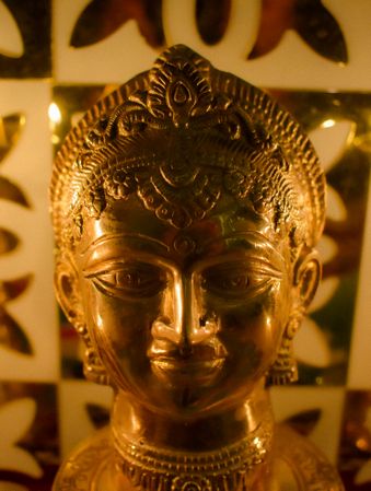 Close-up shot of golden Buddha statue in a candle lit room