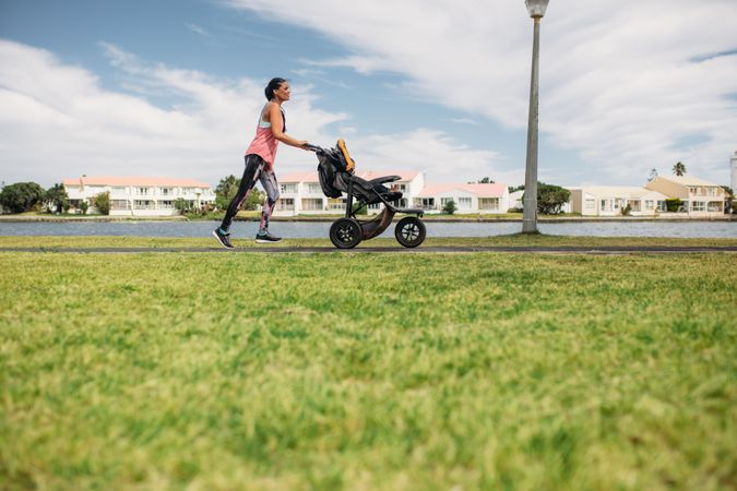 Young mother jogging in park pushing a baby pram