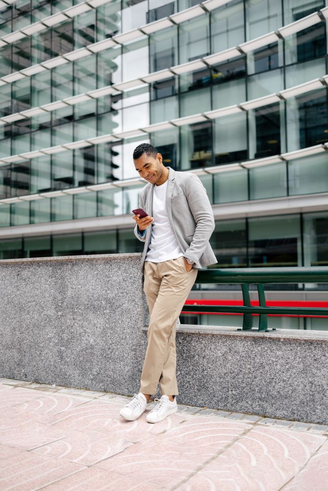 Man using smartphone leaning against wall