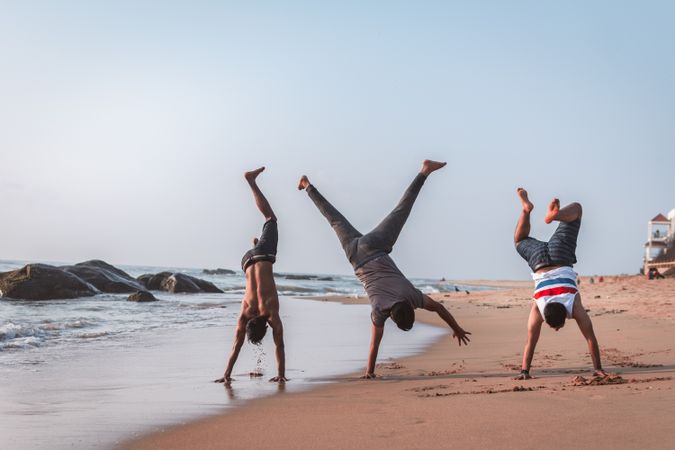 Three boys doing handstand on the beach