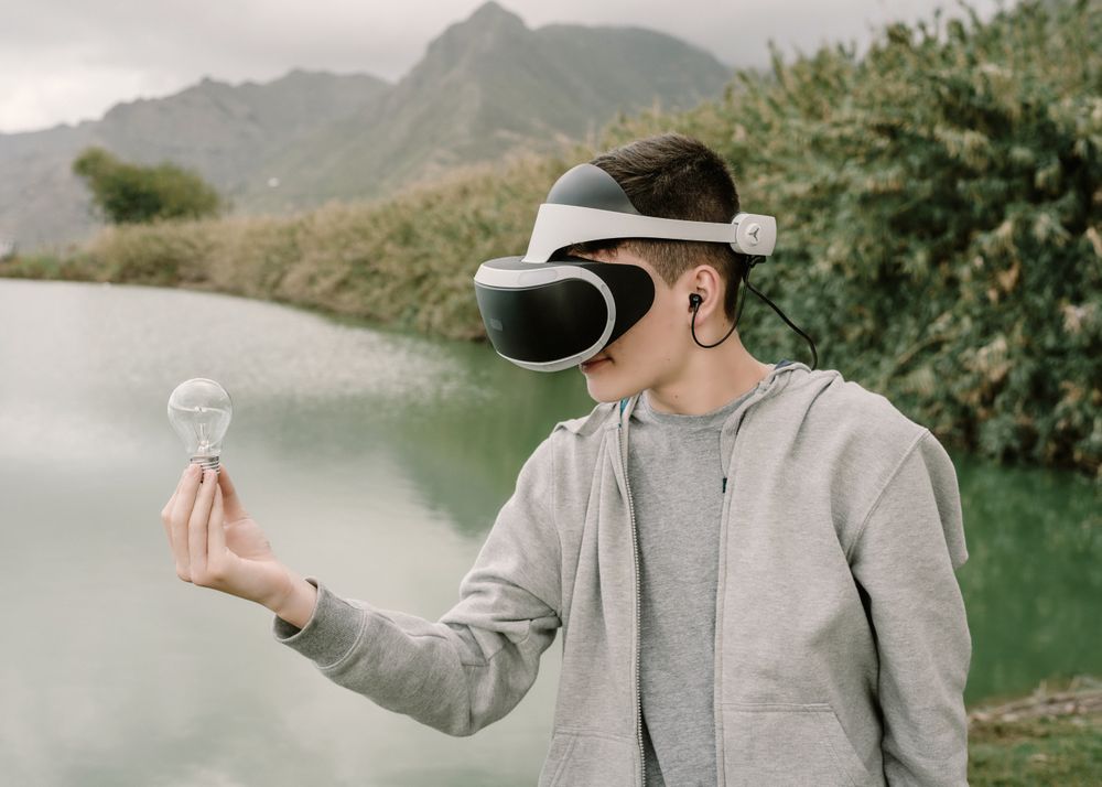 Young teenager with virtual reality glasses holding a light bulb