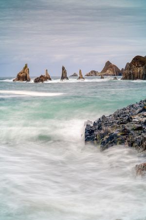 Rocky peaks protrude from water in cloudy day