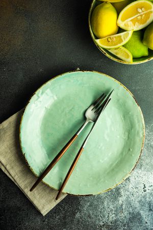 Rustic table setting with light green ceramic plate and bowl of lemons