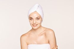 Delighted female with radiant skin applying cream