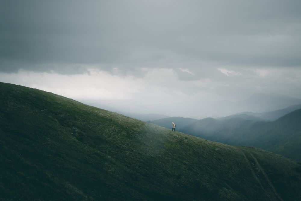 Anonymous traveler walking on path on hillside