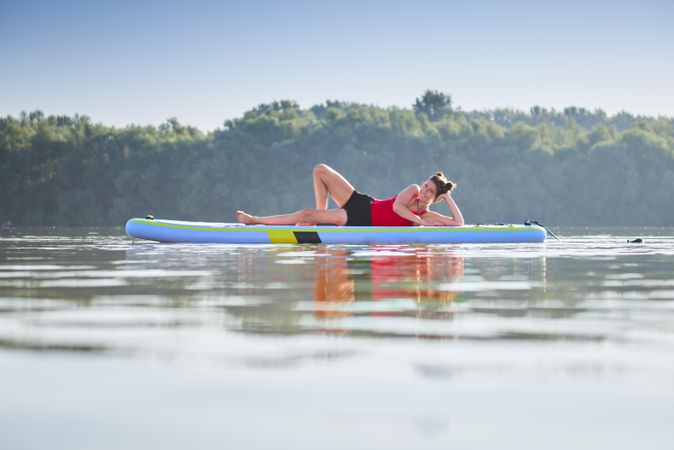 Woman sitting on her side on paddleboard on lake