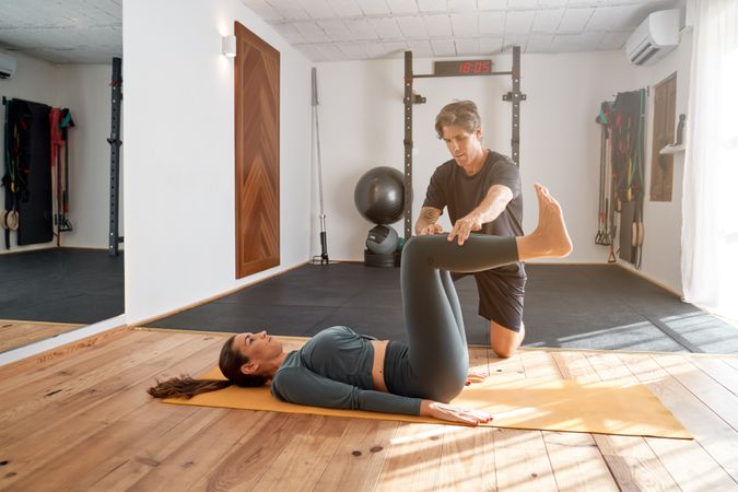 Woman doing yoga in gym with trainer