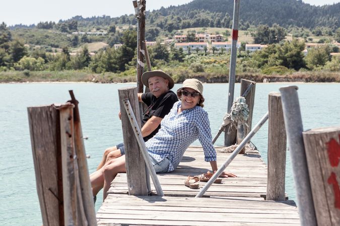 mature couple sitting on dock dangling with legs