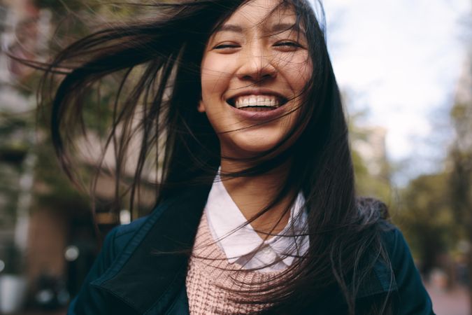 Happy young Asian woman with wind-blown hair