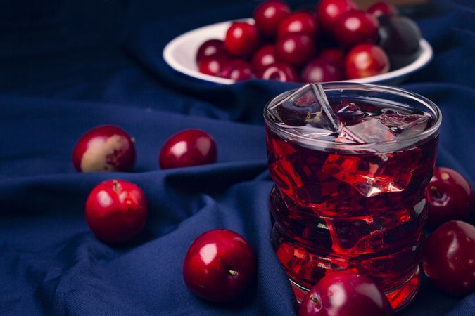 Red beverage near fresh fruits on cloth