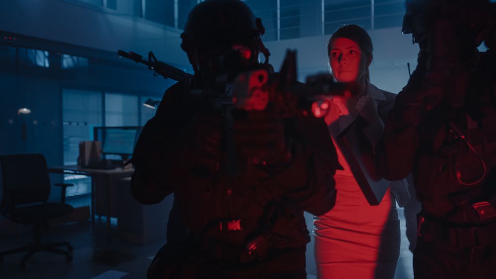 Masked Squad of Armed SWAT Police Officers Rescue a Female Hostage in a Dark Seized Office Building with Desks and Computers.