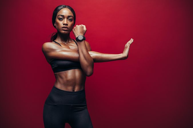 Fit woman doing exercise against red background