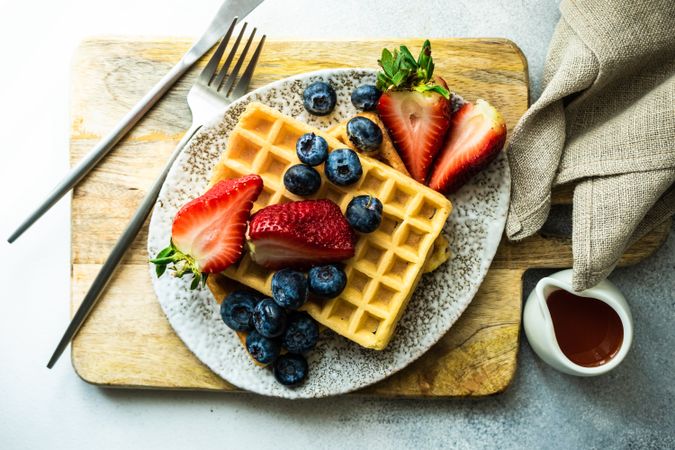 Top view of waffle breakfast with blueberries & strawberries served with syrup