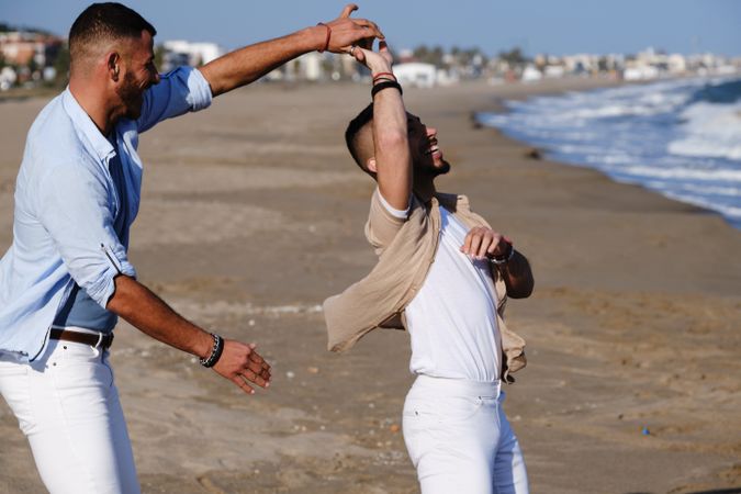 Happy gay couple dancing on seaside