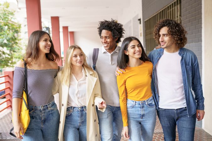 Happy group of friends walking down street outside