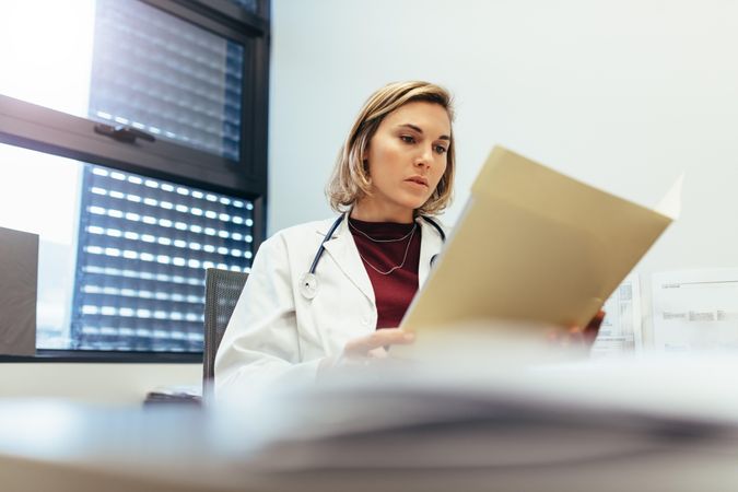 Female doctor sitting in her office and studying medical records