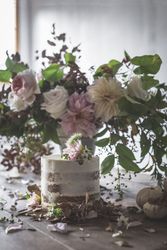 plate with cake decorated flower on table with bouquet of blooms in vase