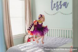 Girl in a cape and purple dress jumping on bed during daytime 4NxEm0