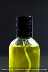Close up of top of yellow bottle with droplets in dark studio 4ZePlW