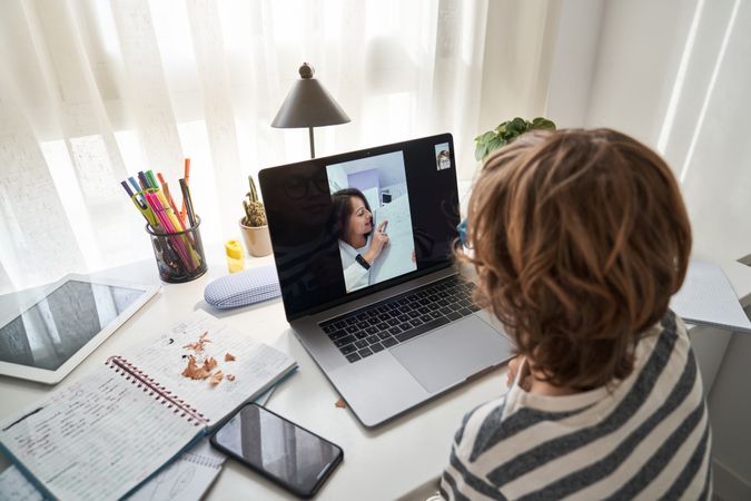 Faceless boy doing schoolwork with girl via laptop