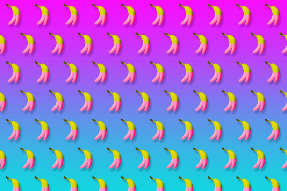 Pink and yellow bananas in rows on gradient pink to blue background