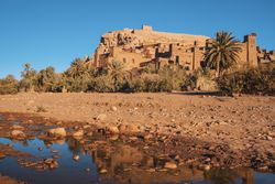 Ancient stone buildings near palms and water