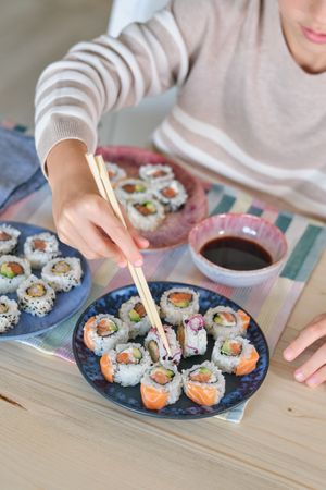 Crop boy enjoying tasty rolls in kitchen at home