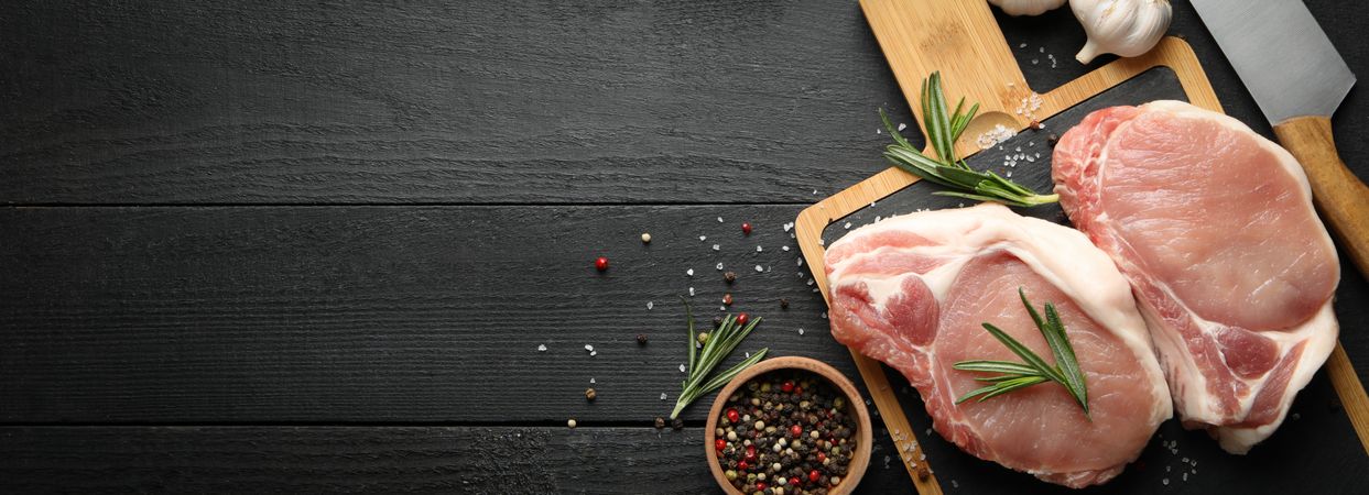 Composition with raw meat for steak and spices on wooden background