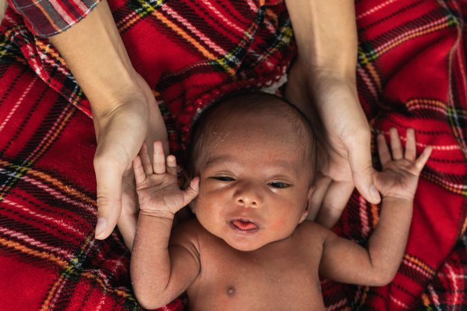 Mother with newborn baby on soft tartan blanket