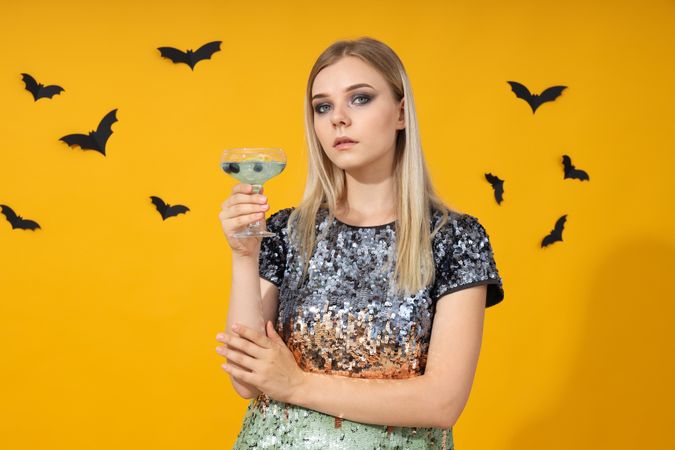 A woman at a party in the style of Halloween with a cocktail in her hands