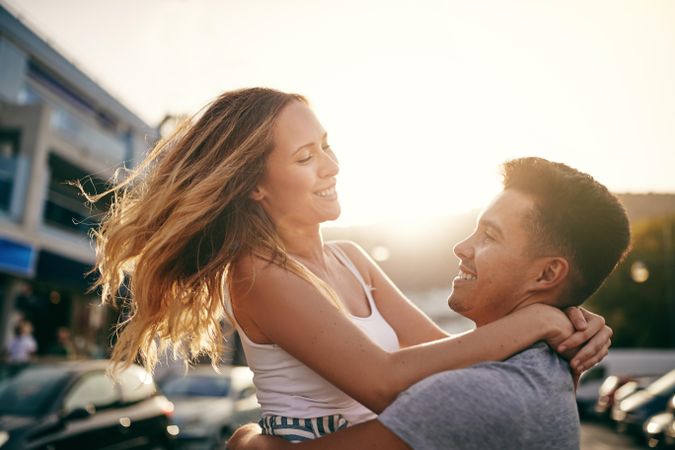 Happy man holding smiling beautiful woman up