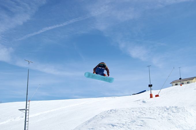 Unrecognizable snowboarder jumping on slope