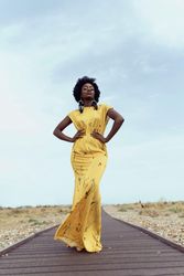 Woman in yellow sleeveless dress standing on asphalt road in desert
