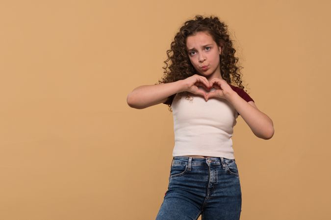 Young girl making heart gesture with hands, expressing affection