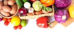 Wicker basket, wood board and vegetables isolated on plain background