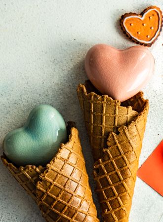 Close up of two ceramic hearts in waffle cones on grey background